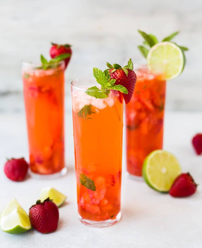Refreshing fruity cocktails garnished with mint, lime, and strawberries